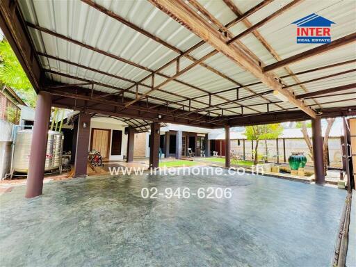 Covered outdoor area with concrete flooring and garden space.