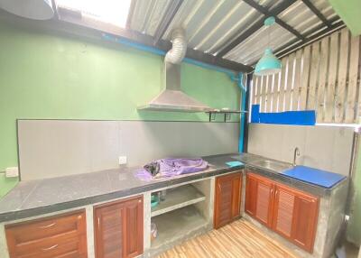 Simple kitchen with green walls, wooden cabinets, stainless steel countertop and range hood