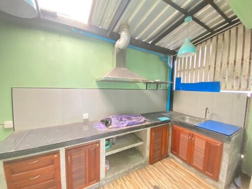 Simple kitchen with green walls, wooden cabinets, stainless steel countertop and range hood