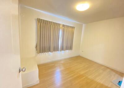 Spacious empty bedroom with hardwood floor and window with curtains