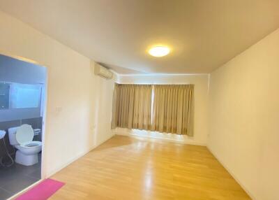 Empty living room with wooden floor and bathroom in view