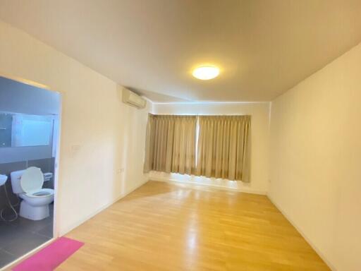 Empty living room with wooden floor and bathroom in view