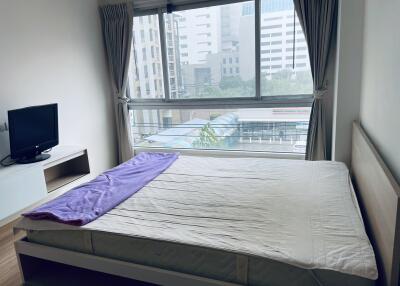 Bedroom with large window and view of city buildings