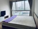 Bedroom with large window and view of city buildings