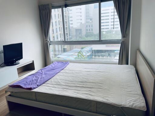 Bedroom with large window and view of city buildings