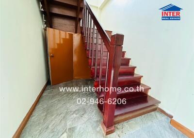 Staircase with a wooden railing and a small storage area underneath