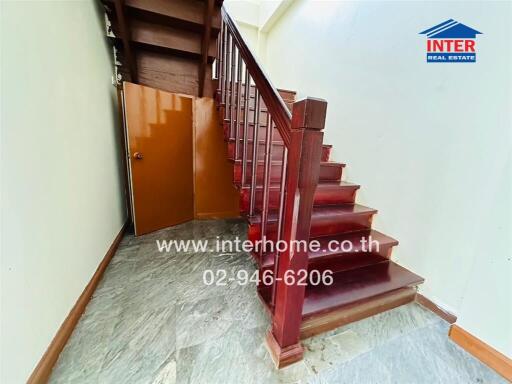 Staircase with a wooden railing and a small storage area underneath