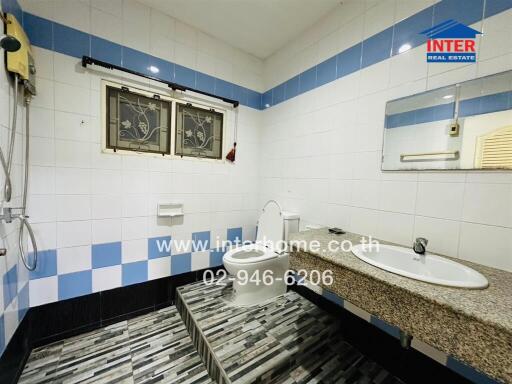 Modern bathroom with tiled walls, shower, toilet, and sink