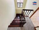 Indoor staircase with wooden steps and railing, window, and tiled flooring at the bottom.