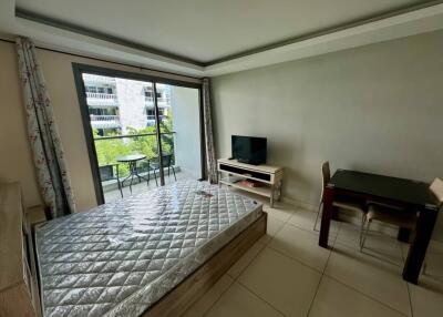 Bedroom with bed, table, chairs, TV, and a balcony