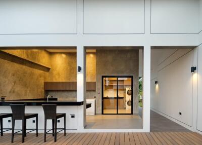 Modern outdoor-indoor kitchen area with bar stools and laundry appliances