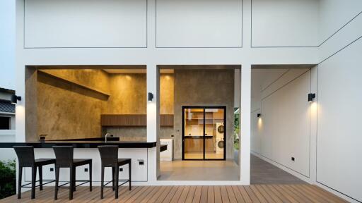 Modern outdoor-indoor kitchen area with bar stools and laundry appliances