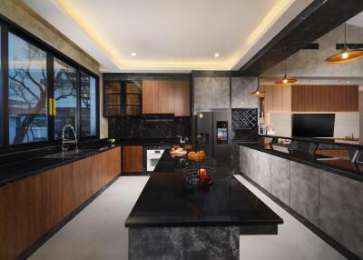 Modern kitchen with black countertops, wooden cabinets, and overhead lighting