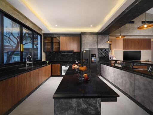 Modern kitchen with black countertops, wooden cabinets, and overhead lighting