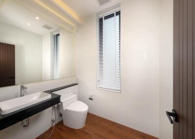 Modern bathroom with a large mirror, sink, and toilet