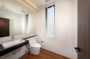 Modern bathroom with a large mirror, sink, and toilet