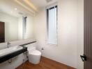 Modern bathroom with a large mirror, sink, and toilet