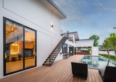 Modern house exterior with glass doors, outdoor seating, and swimming pool