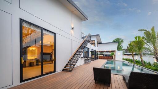 Modern house exterior with glass doors, outdoor seating, and swimming pool