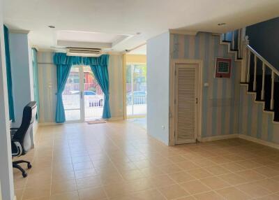 Spacious living room with tiled floor, large windows, and a staircase.