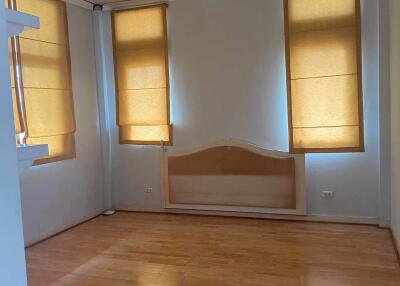 Spacious empty bedroom with wooden flooring and window shades