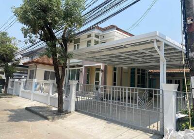 Exterior view of a residential house with a gated driveway and carport