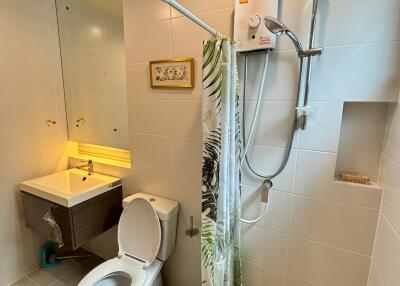 Modern bathroom with a large mirror, toilet, shower, and sink