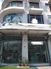 Front view of a modern commercial building with large glass windows and potted plants