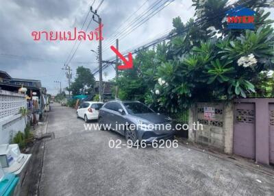 Street view with cars parked, trees, and a sign with contact information