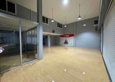 Spacious commercial or industrial building interior with tiled flooring, large glass entrance, high ceilings and numerous overhead lights