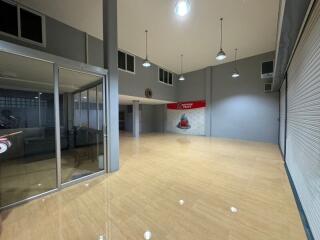 Spacious commercial or industrial building interior with tiled flooring, large glass entrance, high ceilings and numerous overhead lights