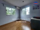 Empty bedroom with wooden floor, windows, wall-mounted AC unit, and desk