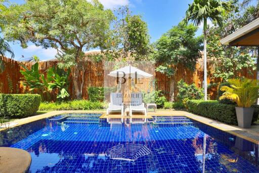 Beautiful outdoor pool surrounded by lush greenery and tall trees