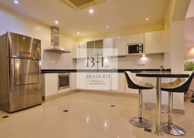 Modern kitchen with stainless steel refrigerator, oven, microwave, and breakfast bar