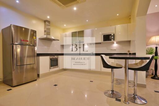 Modern kitchen with stainless steel refrigerator, oven, microwave, and breakfast bar