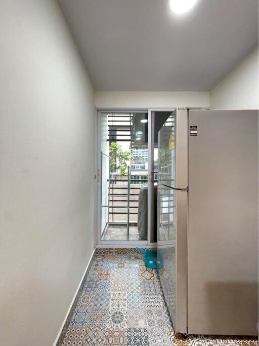 Modern kitchen area with refrigerator and patterned tile floor