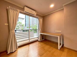 A bright bedroom with a wooden floor and large window