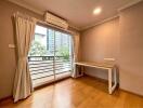 A bright bedroom with a wooden floor and large window