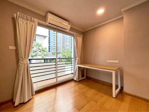 A bright bedroom with a wooden floor and large window