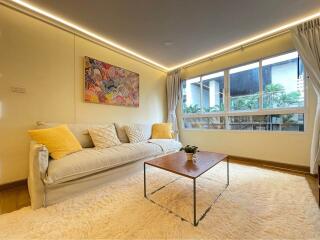 Modern living room with sofa, coffee table, large window, and wall art