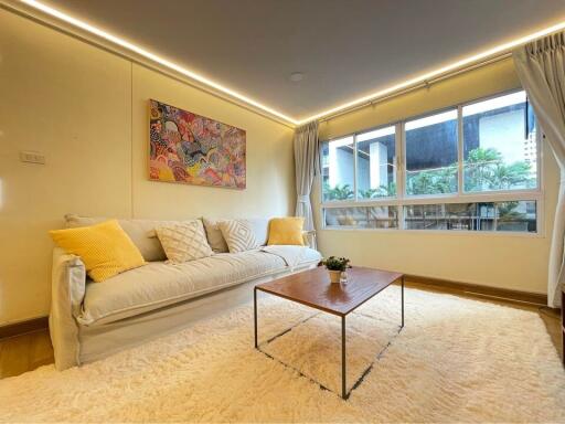 Modern living room with sofa, coffee table, large window, and wall art