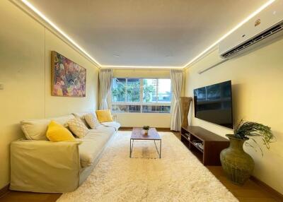 Modern living room with a sofa, coffee table, TV, air conditioner, and large window.