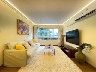 Modern living room with a sofa, coffee table, TV, air conditioner, and large window.