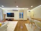 Modern living room with wooden flooring, television, dining table, and air conditioning.