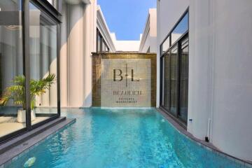 Swimming pool in an upscale property with glass windows and a decorative water feature