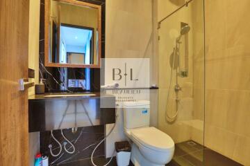 Modern bathroom with glass shower, toilet, sink, and wooden accents