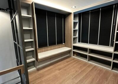 Modern walk-in closet with shelves and a seating area