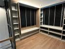 Modern walk-in closet with shelves and a seating area