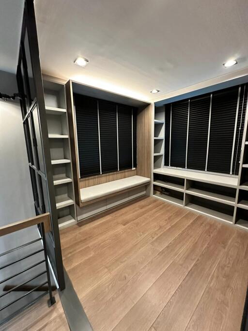 Modern walk-in closet with shelves and a seating area