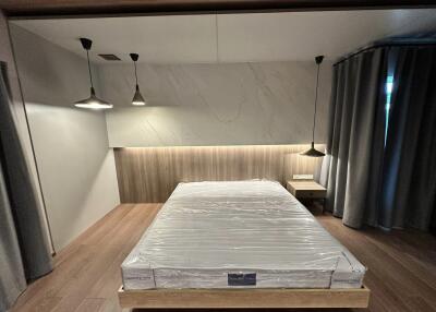 Modern bedroom with hanging lamps and a bed with plastic cover